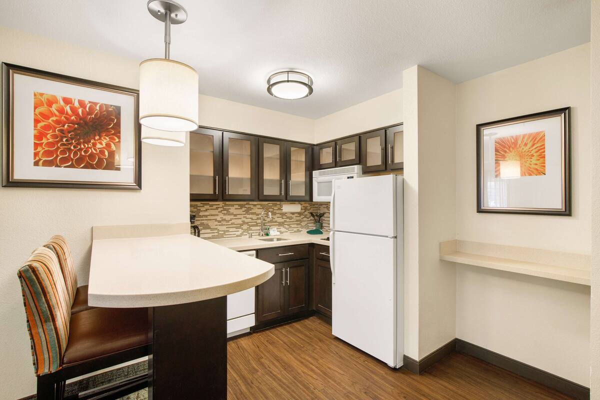 A compact kitchen with a dining area, a refrigerator, and a microwave.