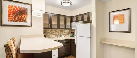 A compact kitchen with a dining area, a refrigerator, and a microwave.