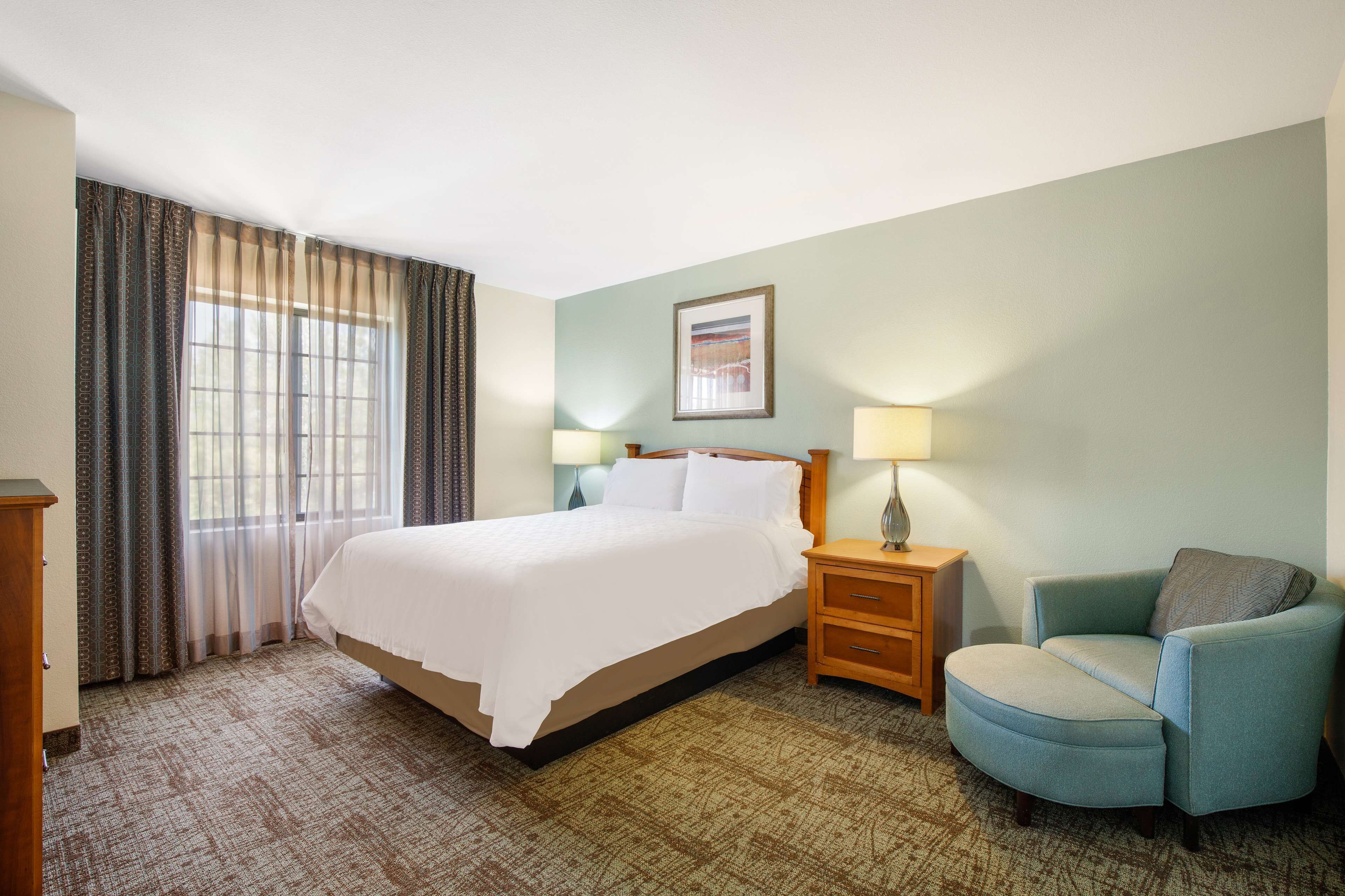 Ein Hotelzimmer mit Bett, Stuhl, Nachttisch und Lampe.