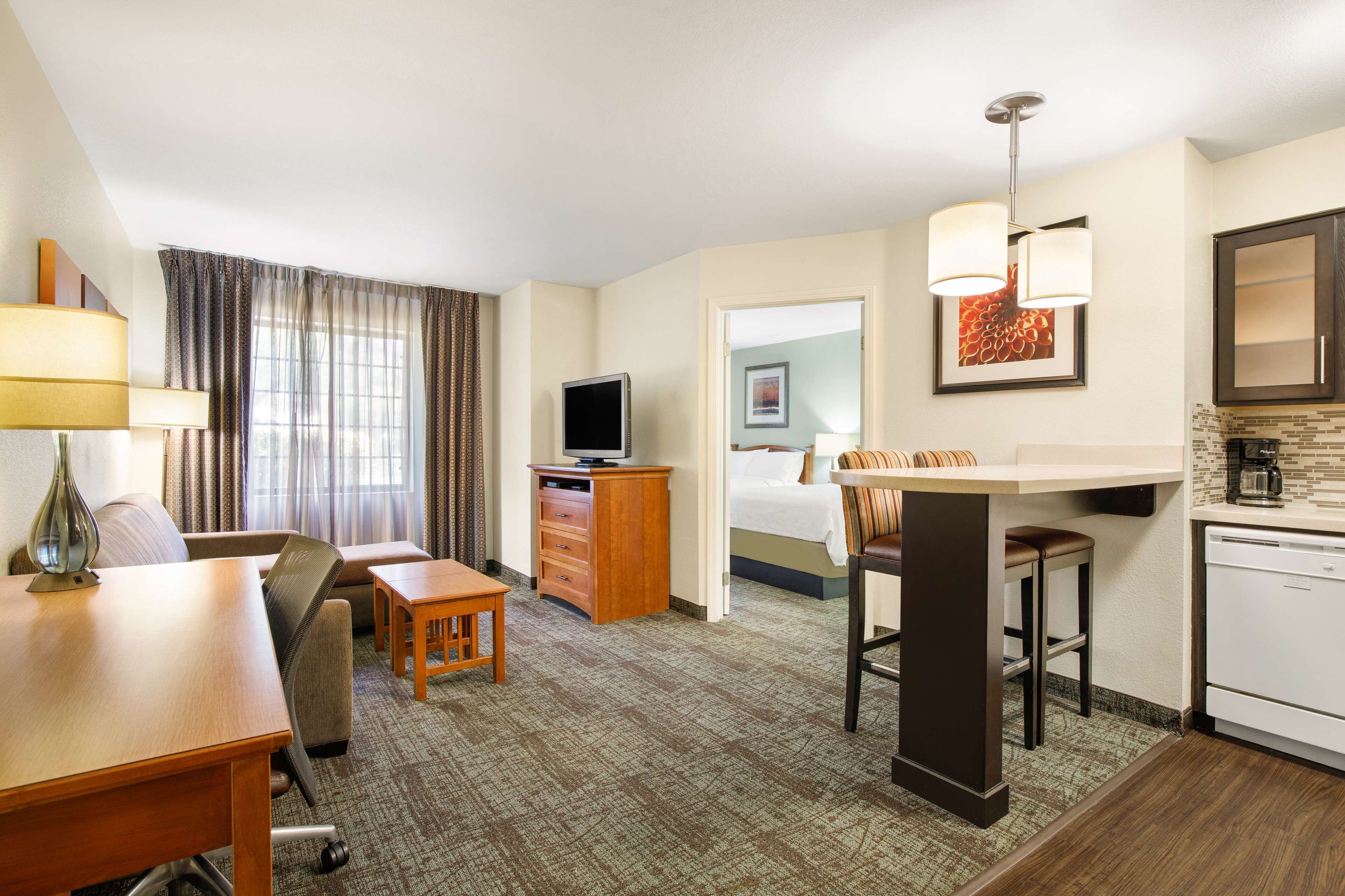 Une chambre d’hôtel équipée d’une kitchenette, d’un coin repas, d’une télévision, d’un lit et d’une salle de bain.