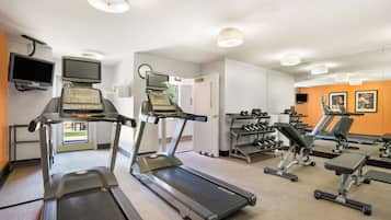 Une salle de sport équipée de tapis de course, d’appareils de musculation et d’un téléviseur.