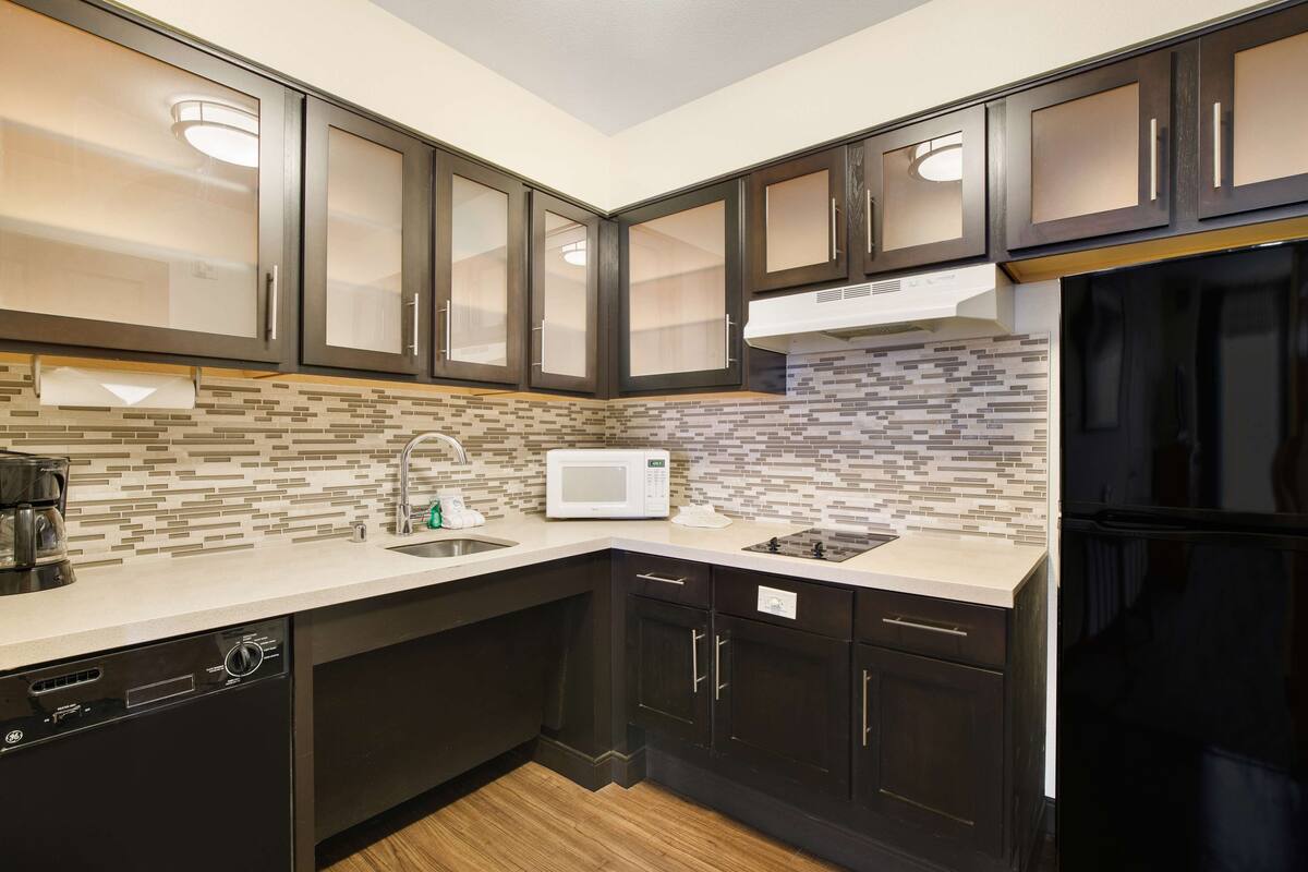 A modern kitchen with dark cabinetry, a microwave, and a dishwasher.