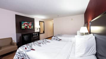 Hotellihuone, jossa on sänky, televisio, työpöytä, lamppu ja sohva.