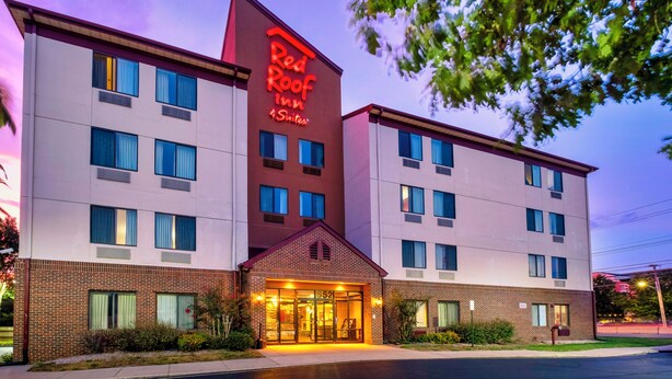 A hotel with a prominent red sign, multiple windows, and a brick facade. - Red Roof Inn & Suites Dover Downtown (Dover)