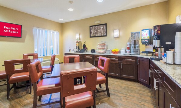 A hotel room with a dining area, kitchenette, and a sign indicating free Wi-Fi in all rooms. - Red Roof Inn & Suites Dover Downtown (Dover)