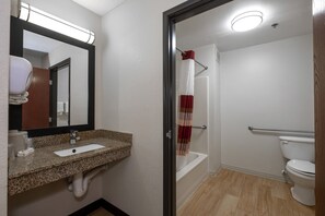 A bathroom with a sink, mirror, toilet, and shower. - Red Roof Inn & Suites Dover Downtown (Dover)