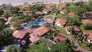 Vista aérea de un resort con varias villas, una piscina y una playa.