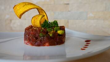 A dish with a banana slice on top, garnished with parsley and avocado, served on a white plate.