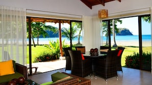 Una habitación con vista a la playa, muebles de mimbre y una mesa con adornos.