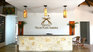 Un mostrador de recepción con fachada de piedra, un logotipo de palmera y tres lámparas colgantes.