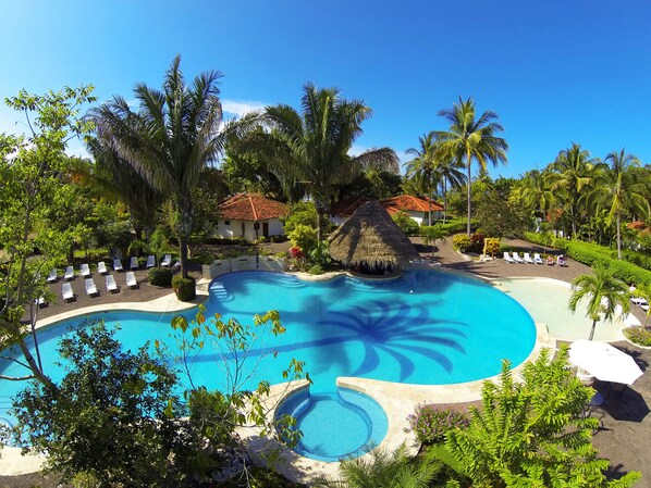 Una piscina al aire libre, sombrillas, sillones reclinables de piscina