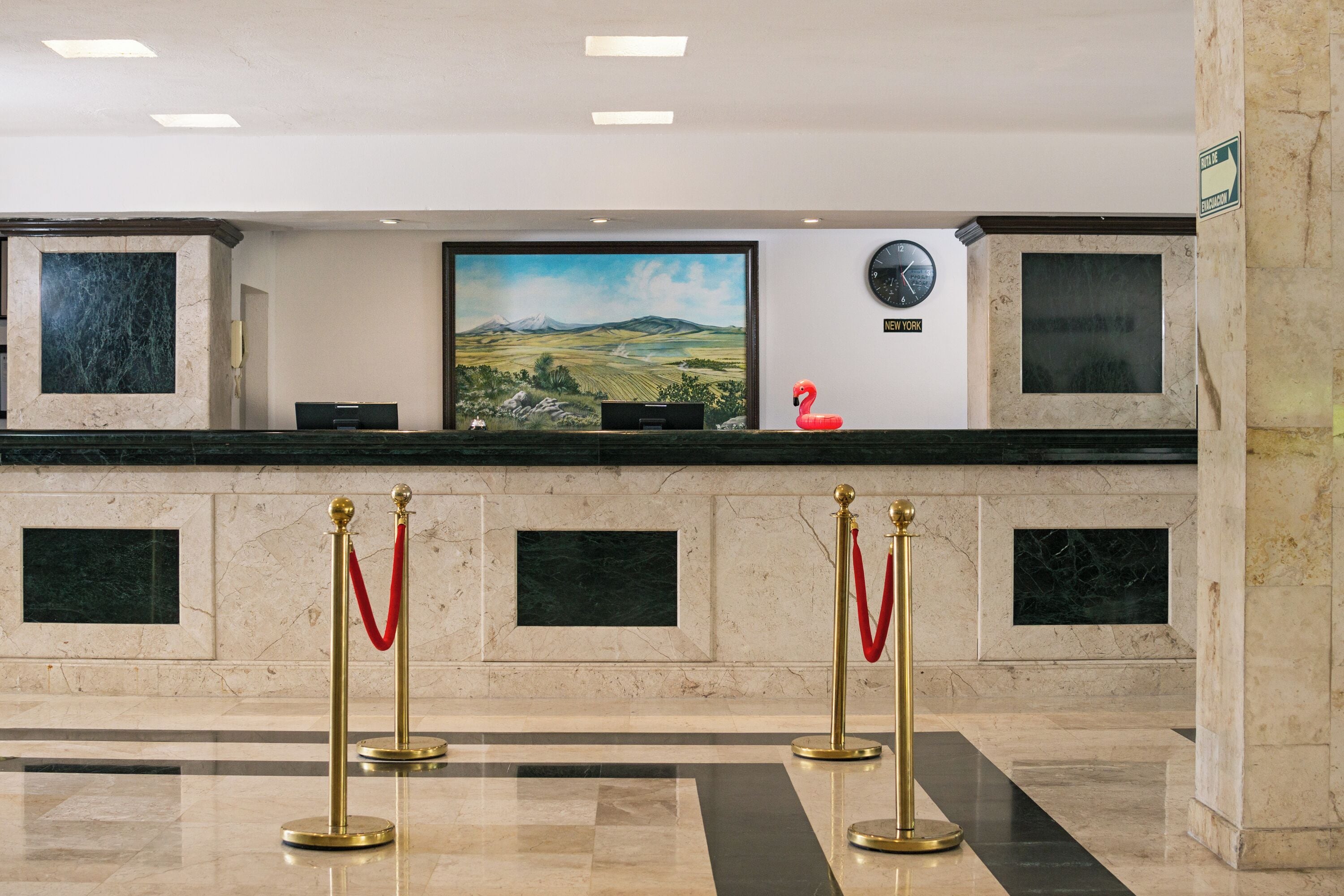 En reception med et ur, et maleri og en rød flamingo som pynt.