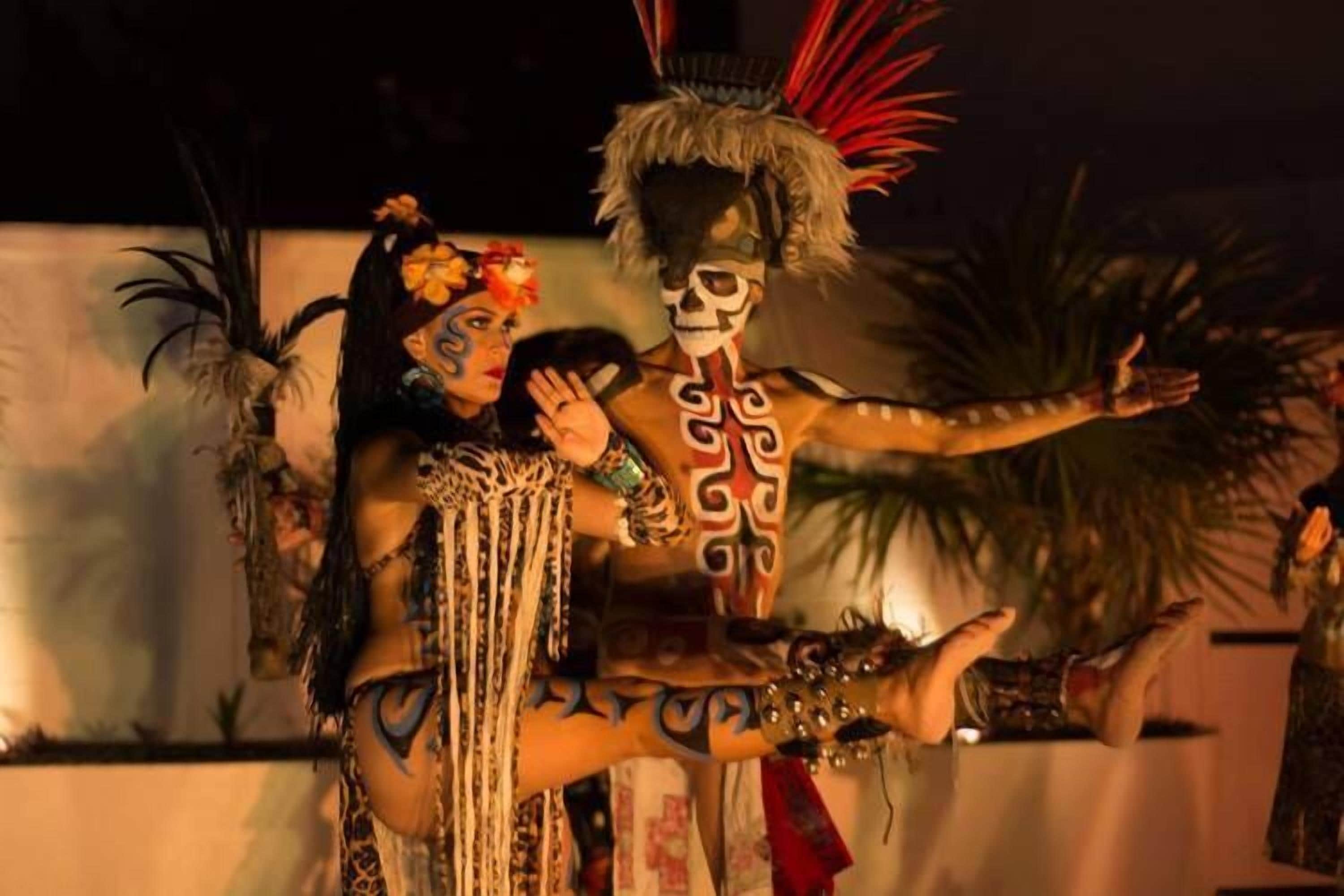 A person in traditional attire with a feathered headdress and body paint.