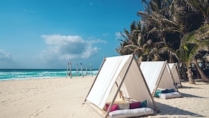 Une plage avec des tentes et des palmiers.