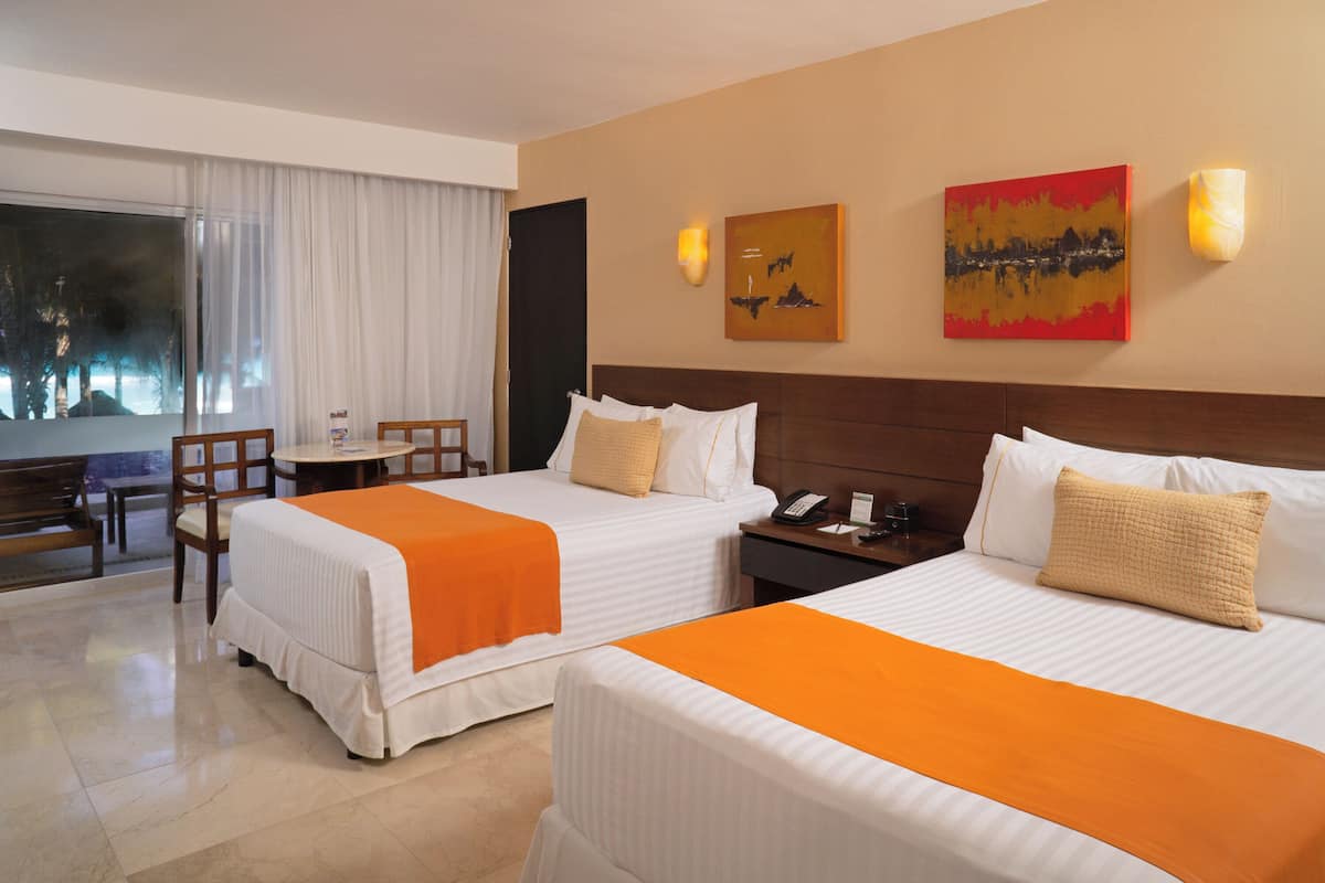Een hotelkamer met twee bedden, een bureau, een stoel en kunstwerken aan de muur.
