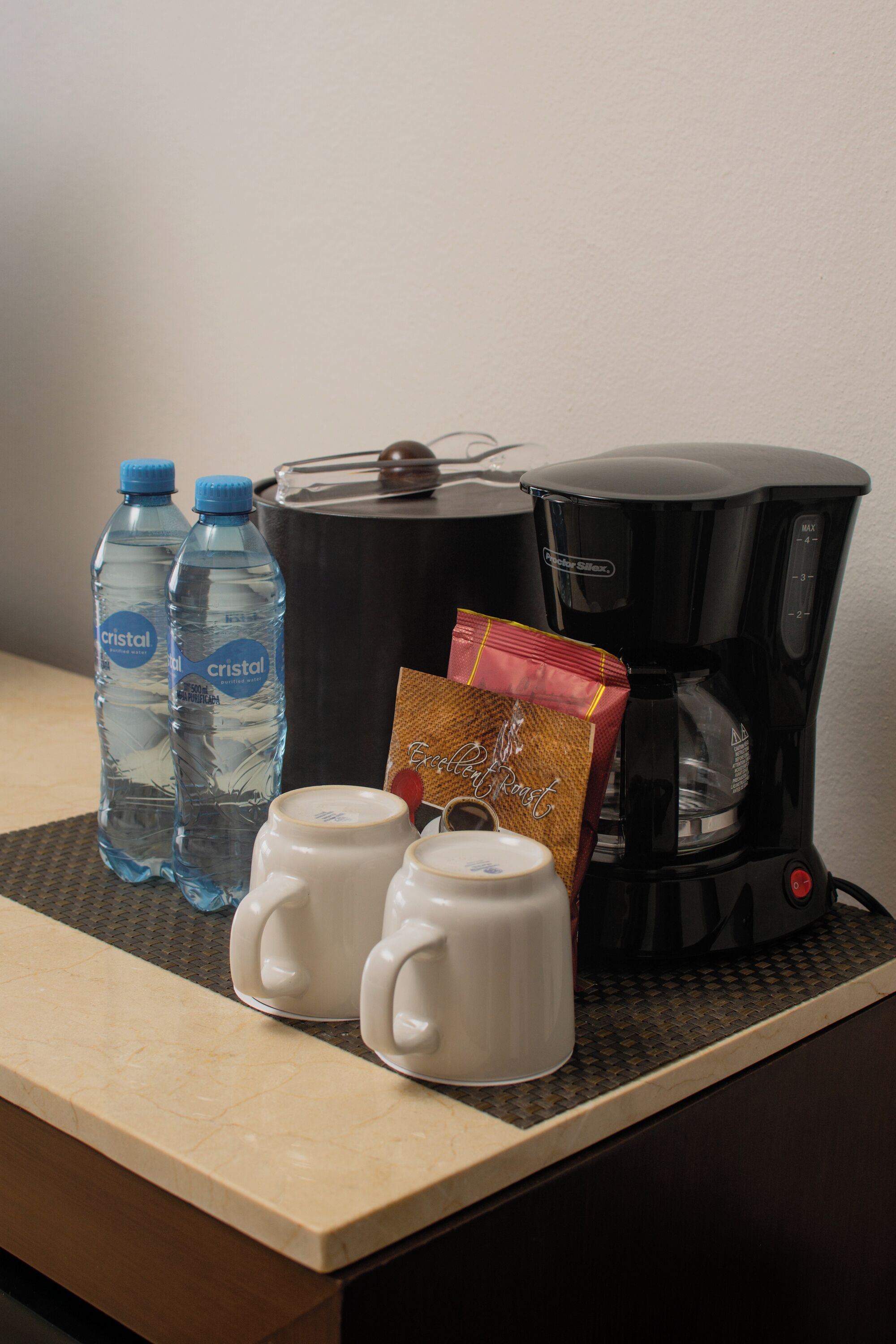 A kitchen counter with two water bottles, a coffee maker, and a packet of coffee.