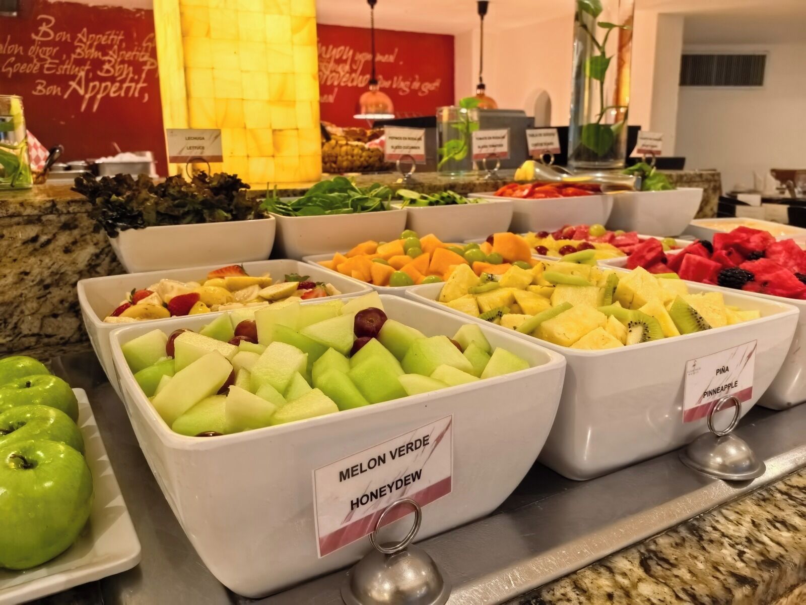 A buffet with various fruits and vegetables, including melon verde and honeydew.