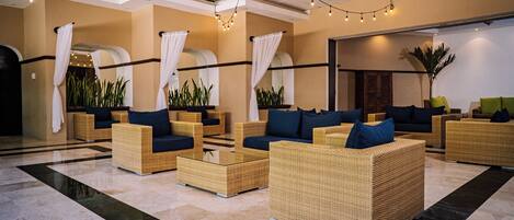 A lobby with wicker furniture, a chandelier, and potted plants.