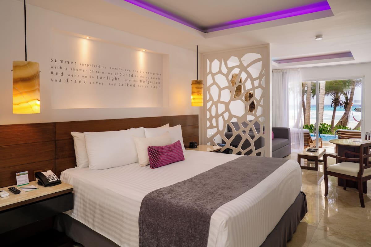 Een hotelkamer met een groot bed, een bureau met telefoon en uitzicht op de oceaan.