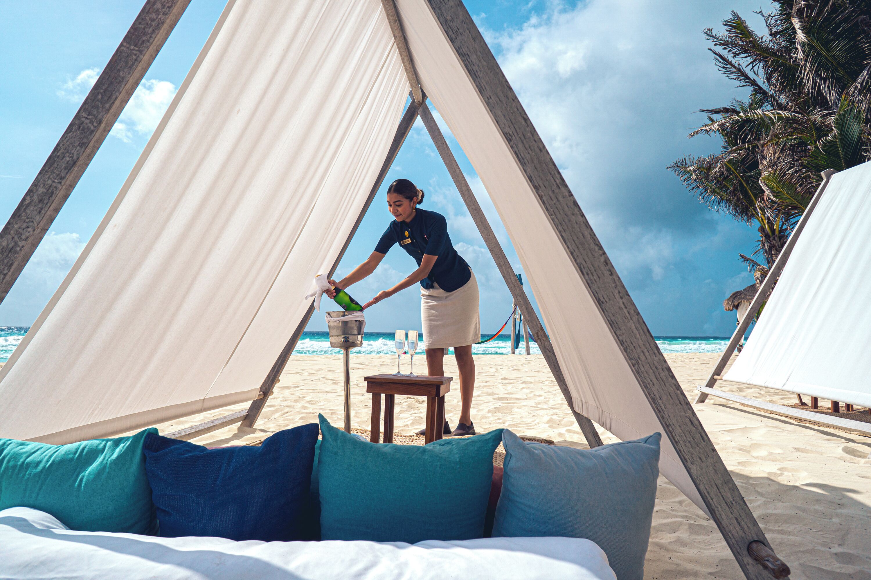 A beach tent with a bed inside, a bucket, and a bottle.