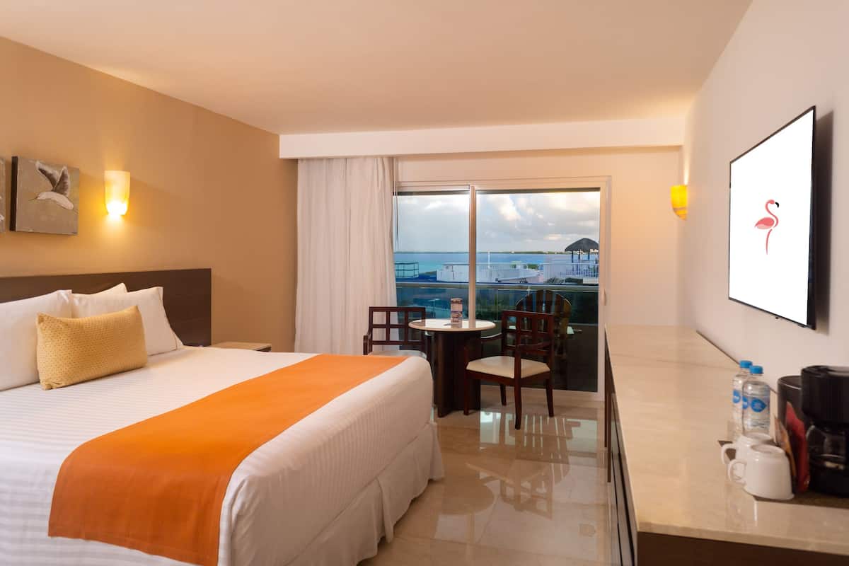 Een hotelkamer met een bed, een kleine tafel met stoelen, een koffiezetapparaat en uitzicht op zee.