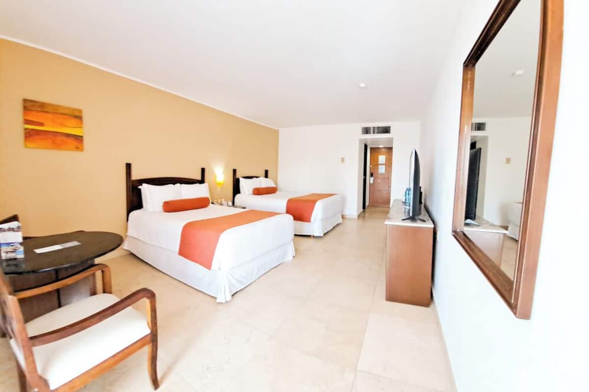Een hotelkamer met twee bedden, een bureau, een stoel, een televisie en een spiegel.
