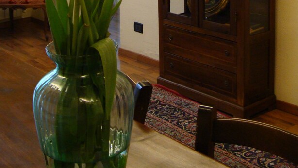 A room with a wooden cabinet, a vase with flowers, and a chair. - Soggiorno Michelangelo (Florence)