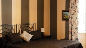 A bedroom with a bed, a red chair, a lamp, and a painting on the wall. - Soggiorno Michelangelo (Florence)