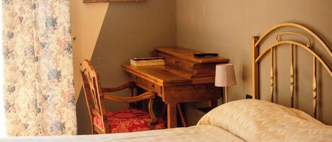A bedroom with a bed, a desk, a chair, and a lamp.