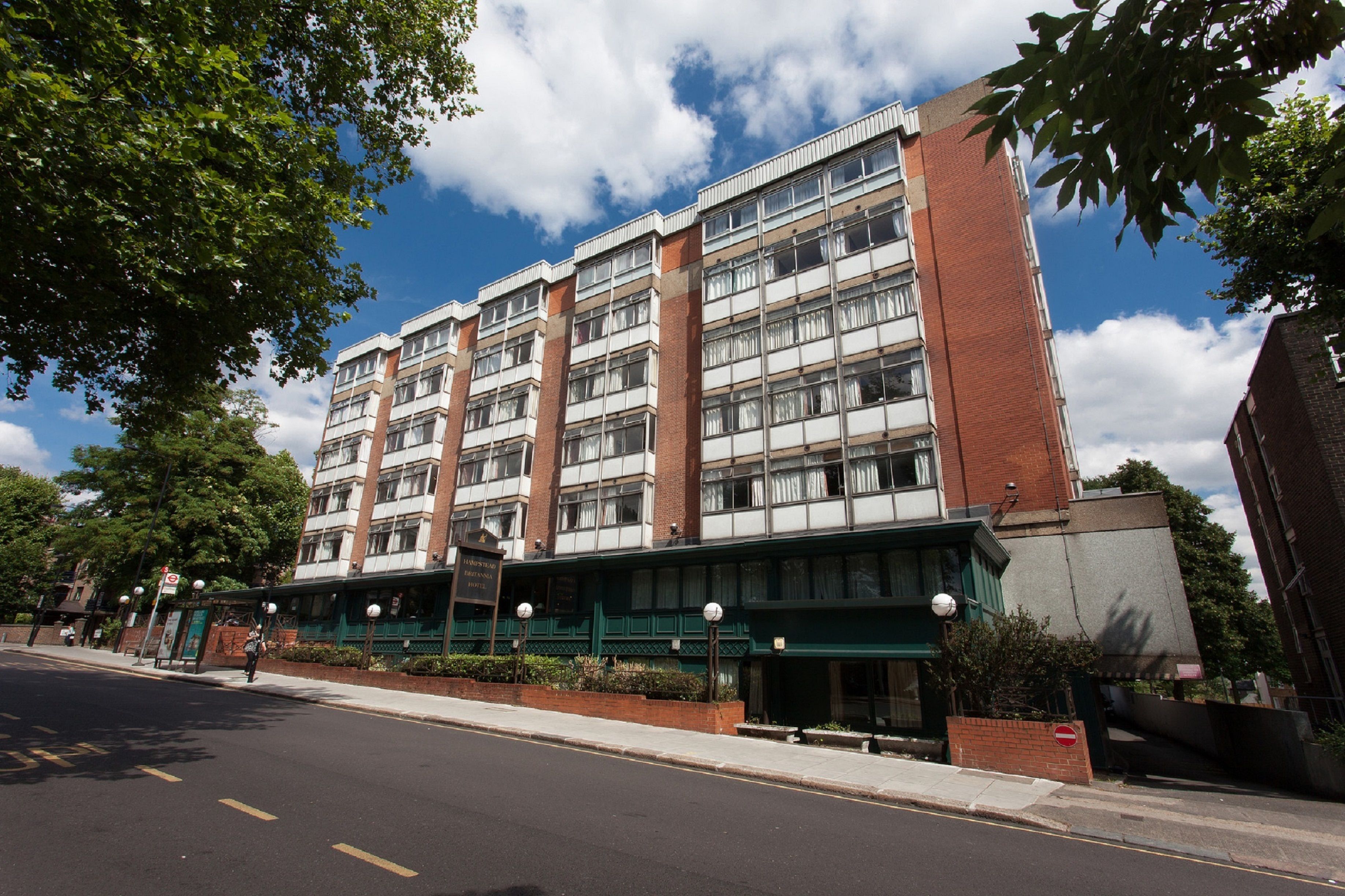 A multi-story hotel with a brick facade, large windows, and a green awning.