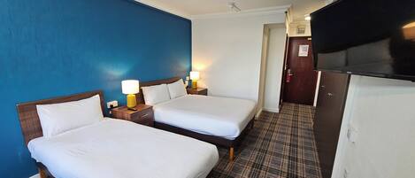 A hotel room with two beds, a TV, and a minibar.