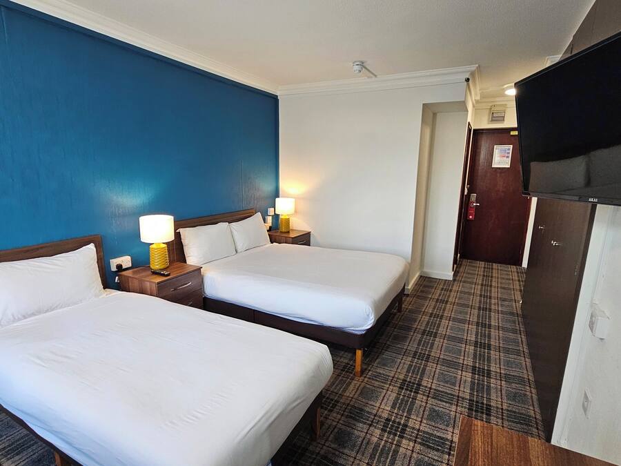 Quarto de hotel com duas camas, televisão e minibar.