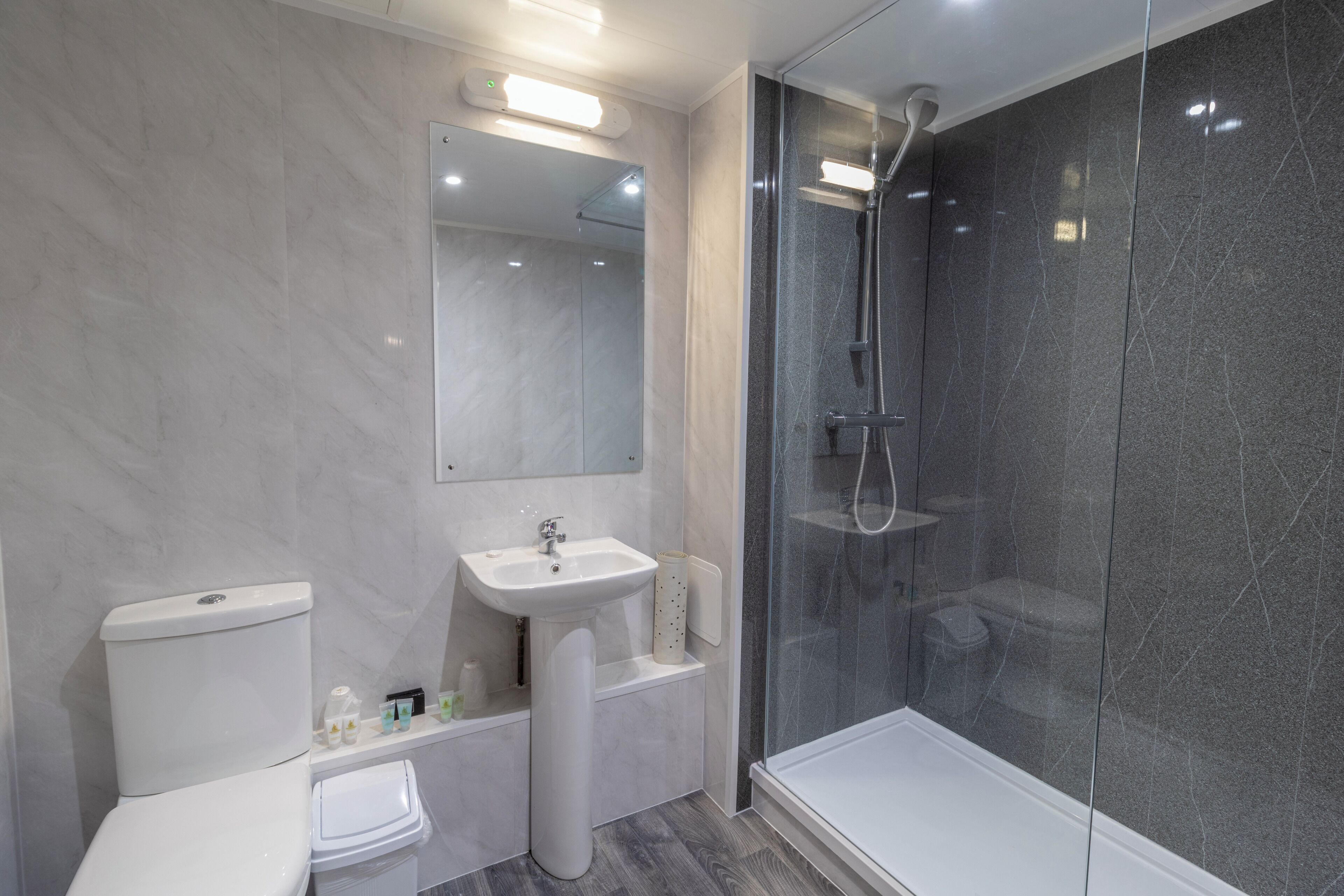A modern bathroom with a toilet, sink, and glass-enclosed shower.
