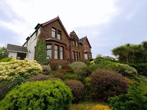 A large, two-story house with a steep roof and a prominent chimney. - Belvedere (Isle of Arran)