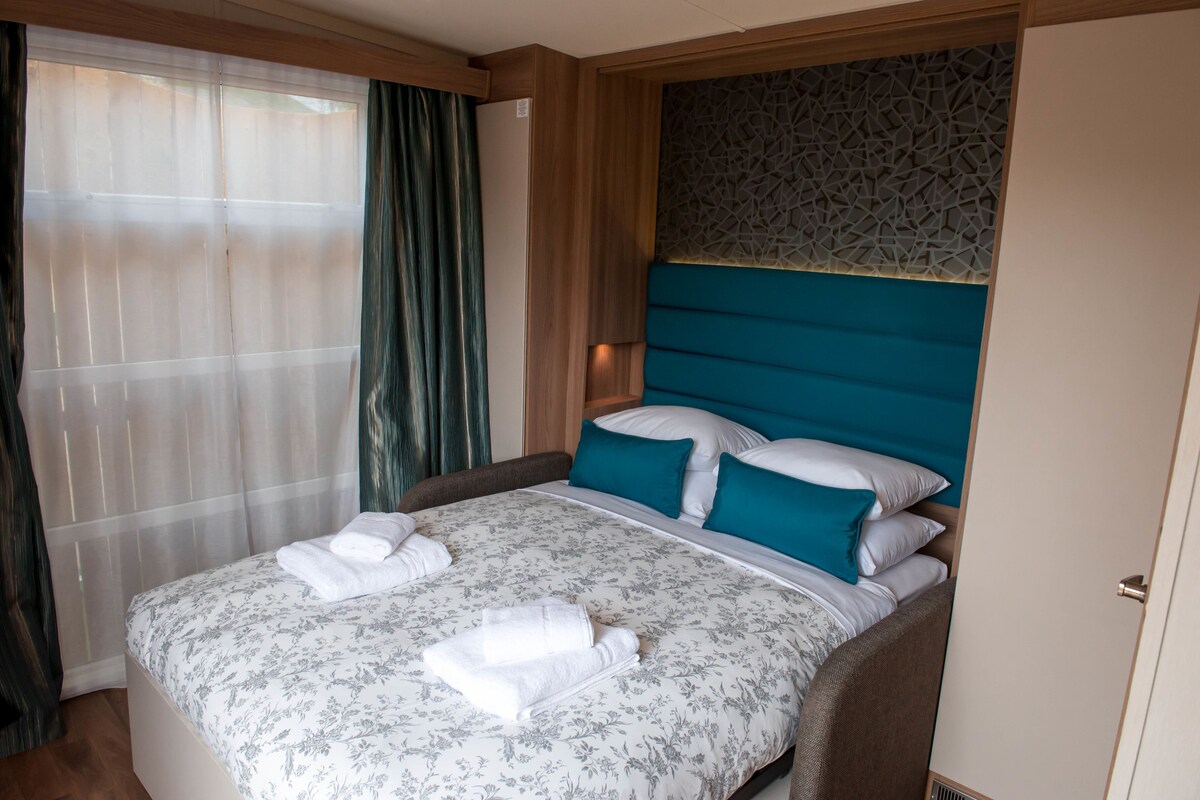A hotel room with a bed, curtains, and a patterned headboard.