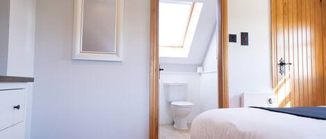 A bedroom with a bed, a wooden door, a window, and a white wall.