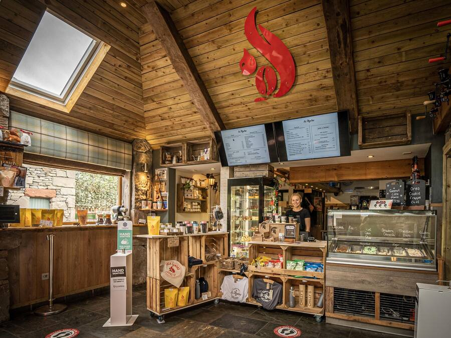 Ein gemütliches Café mit Holzvertäfelungen, einer Glastheke voller Desserts und einer Speisekarte über der Theke.
