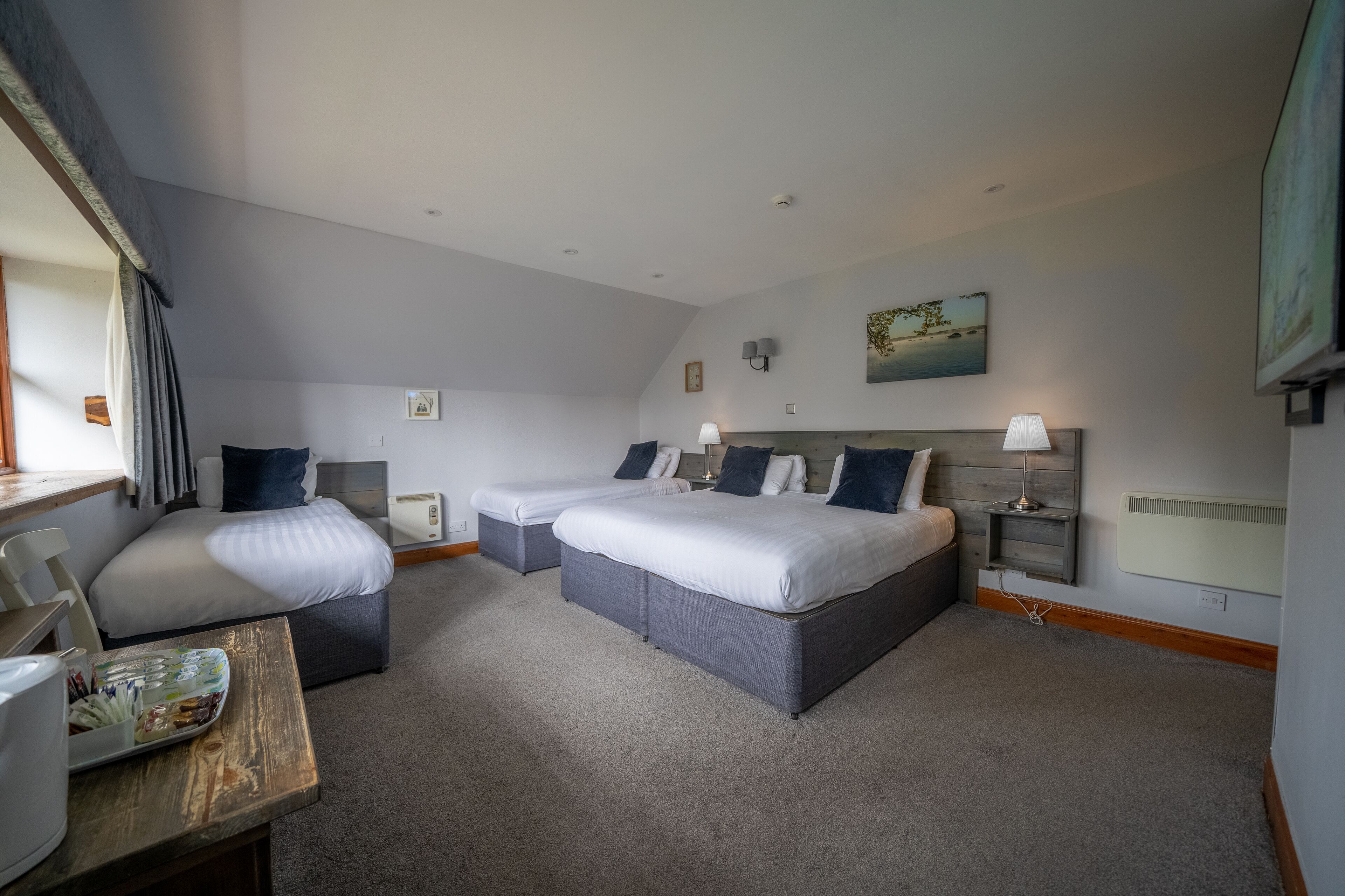 A hotel room with two beds, a desk, and a chair.