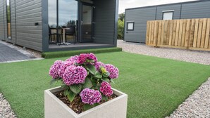 A modern building with a patio and a garden with pink flowers. - The Oak Tree Inn (Balmaha)