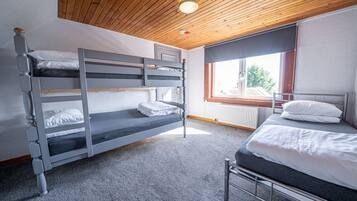 Une chambre avec un lit superposé, un plafond en bois et une fenêtre.
