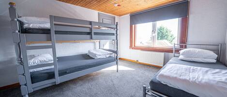 Habitación con literas, techo de madera y ventana.