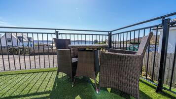 Ein Balkon mit Korbmöbeln und Blick auf das Meer.