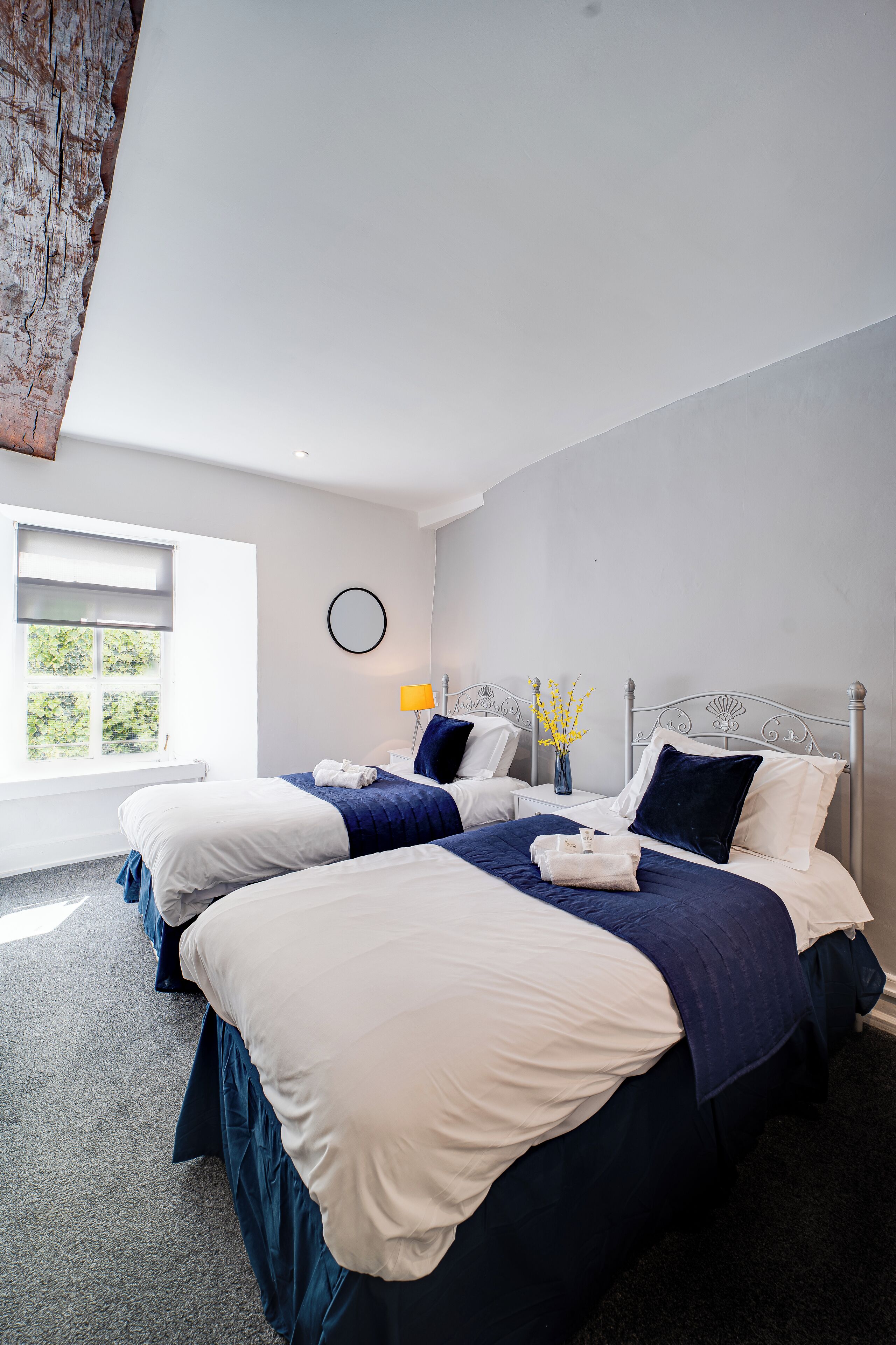 Une chambre d’hôtel moderne avec deux lits, une grande fenêtre et une vue sur la verdure.