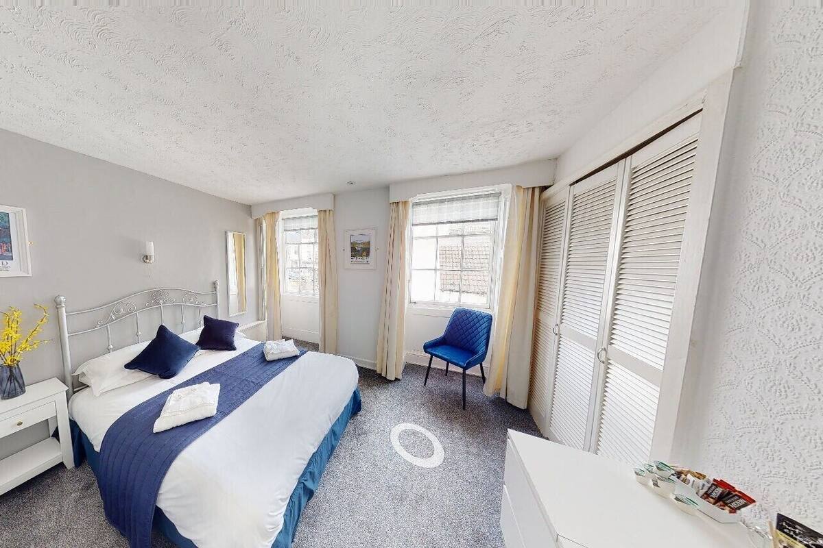 A hotel room with a bed, bedside tables, a chair, and a window with curtains.