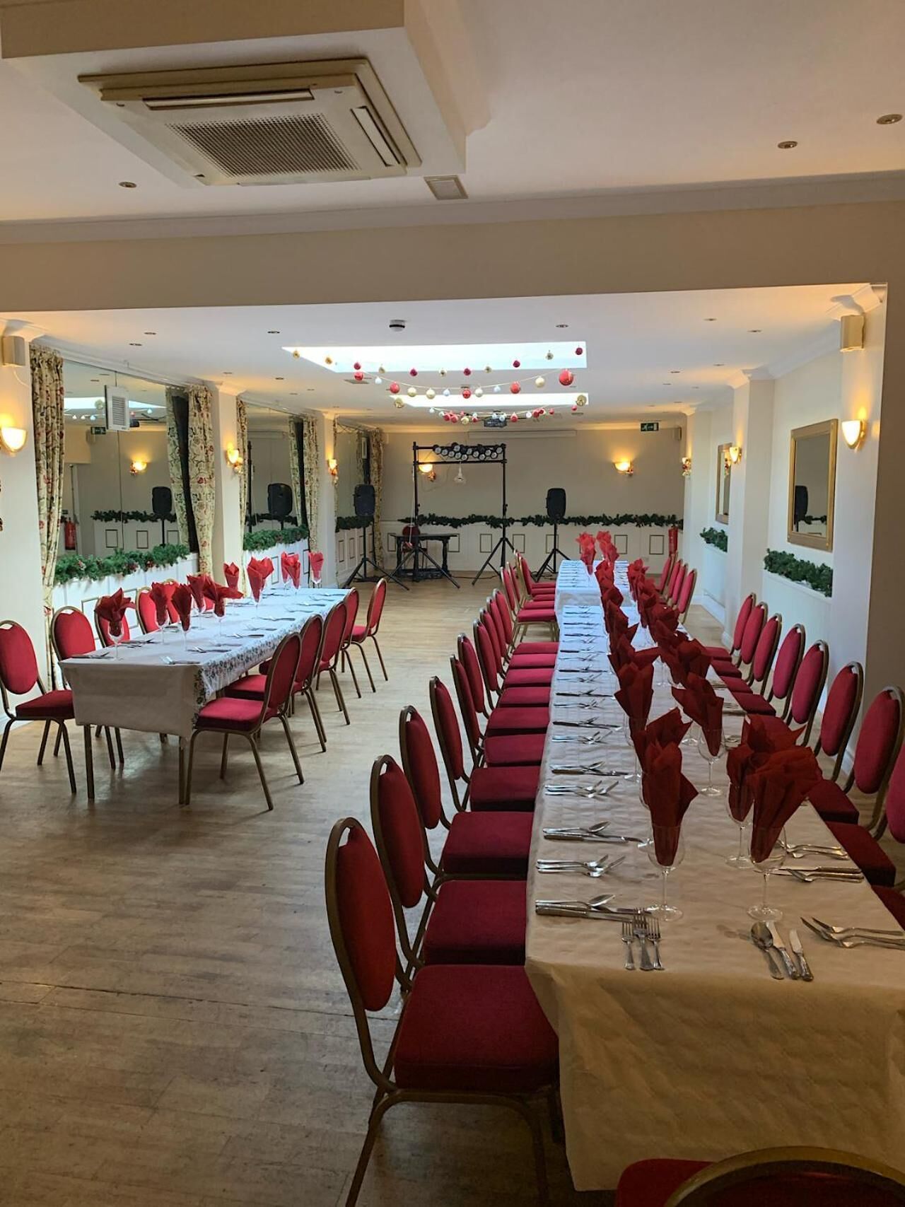 Une salle de banquet avec de longues tables dressées pour un événement formel, équipée de chaises et de couverts.