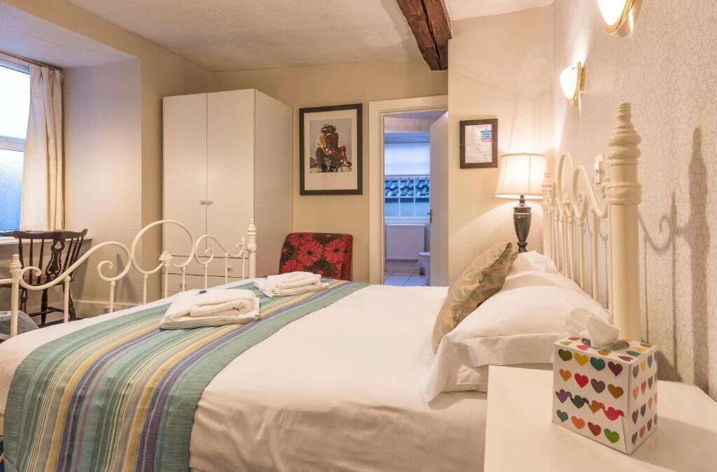 Un dormitorio ordenado con cama, mesita de noche y una silla.