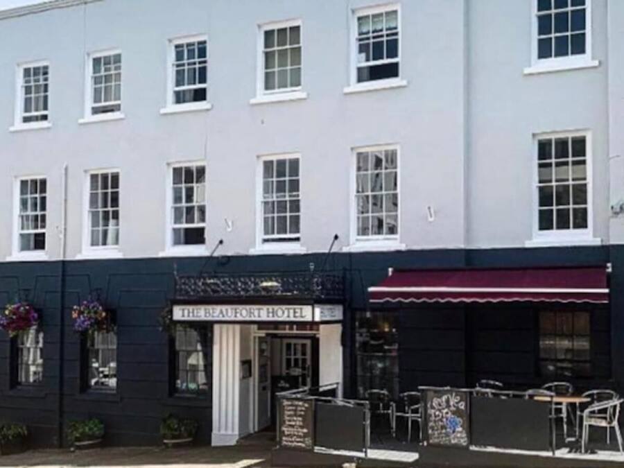 A hotel with a sign reading "The Beaufort Hotel" and outdoor seating with tables and chairs.
