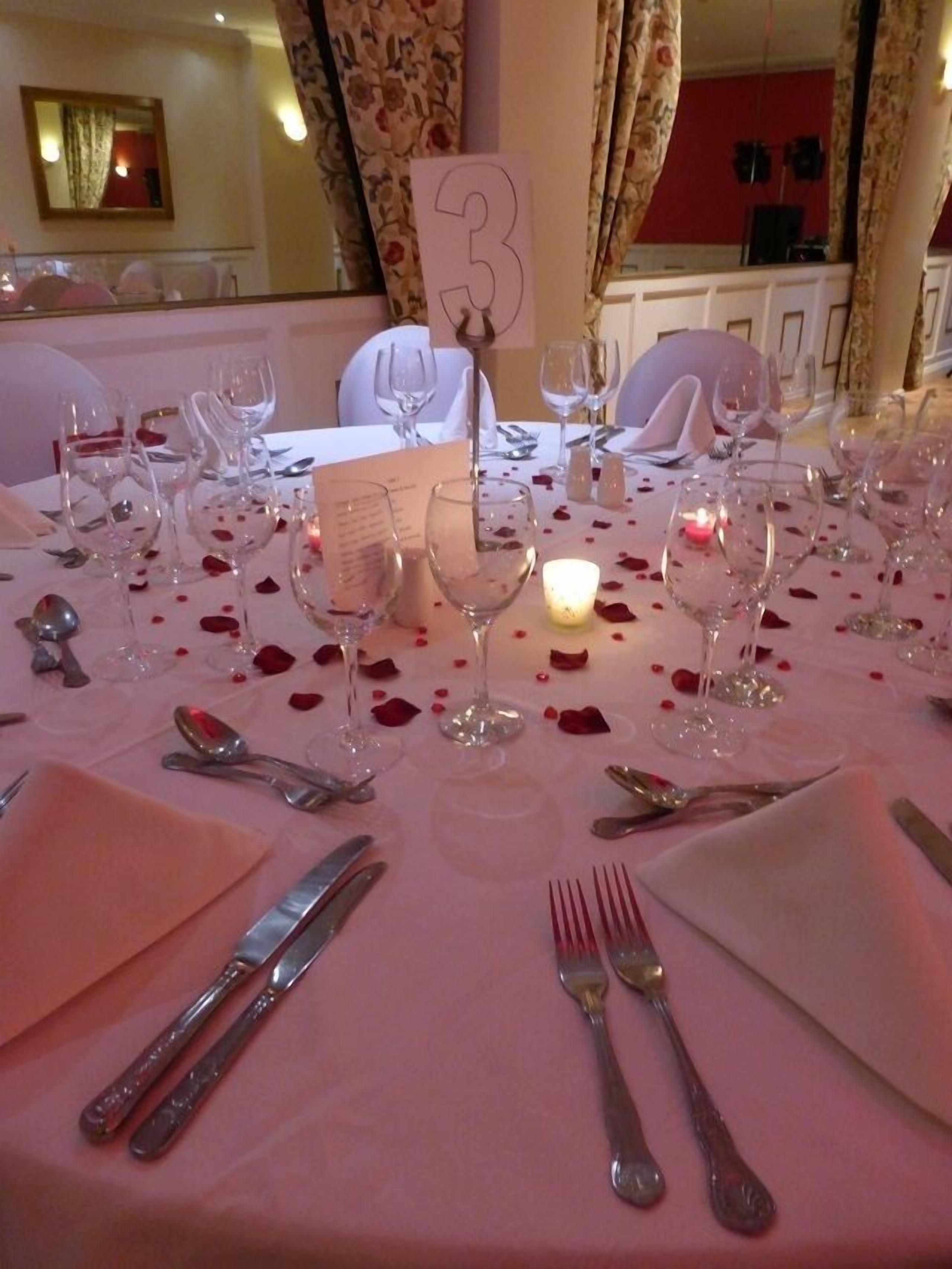 A table set for a meal with numbered place settings, wine glasses, and a candle.
