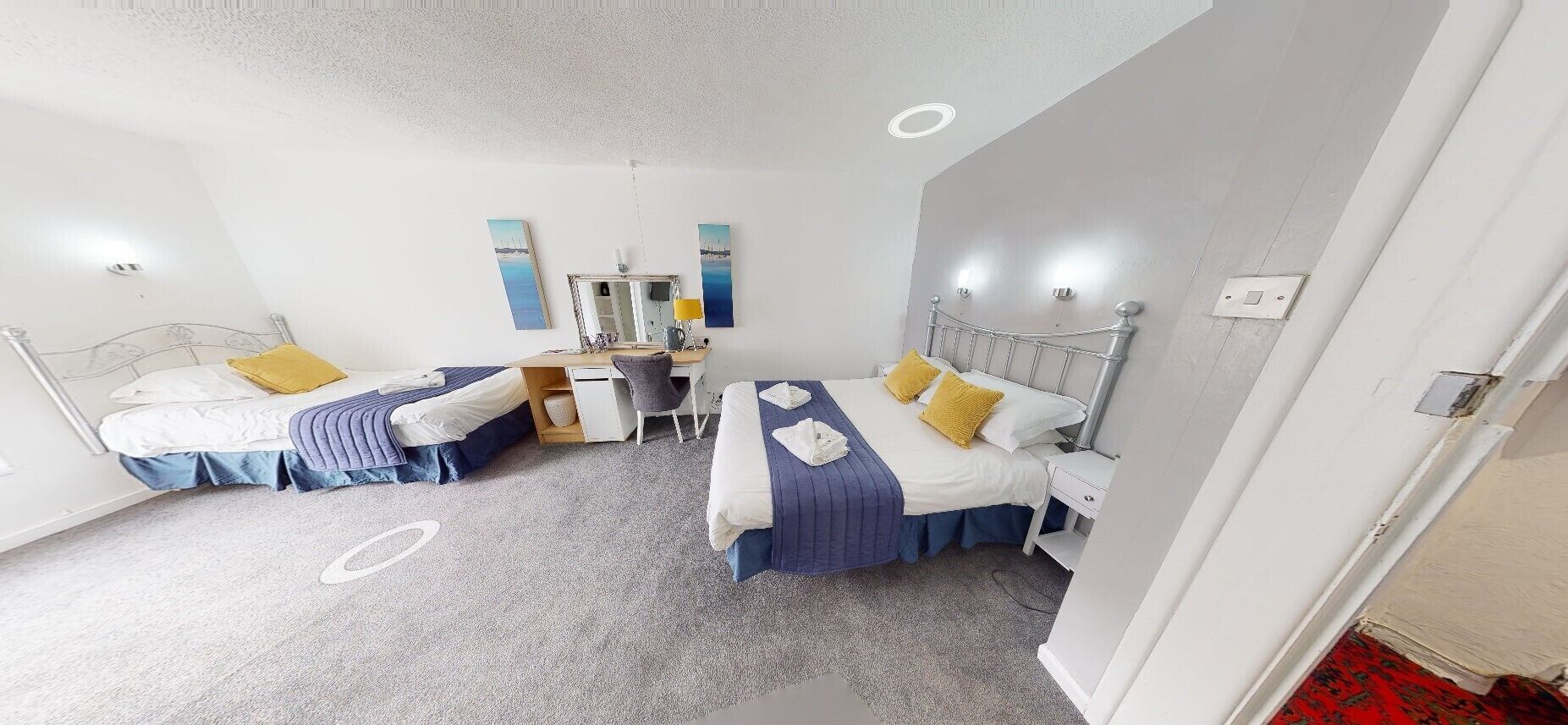 Une chambre d’hôtel avec deux lits, un bureau et un miroir.