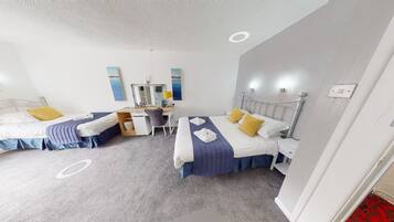 A hotel room with two beds, a desk, and a mirror.
